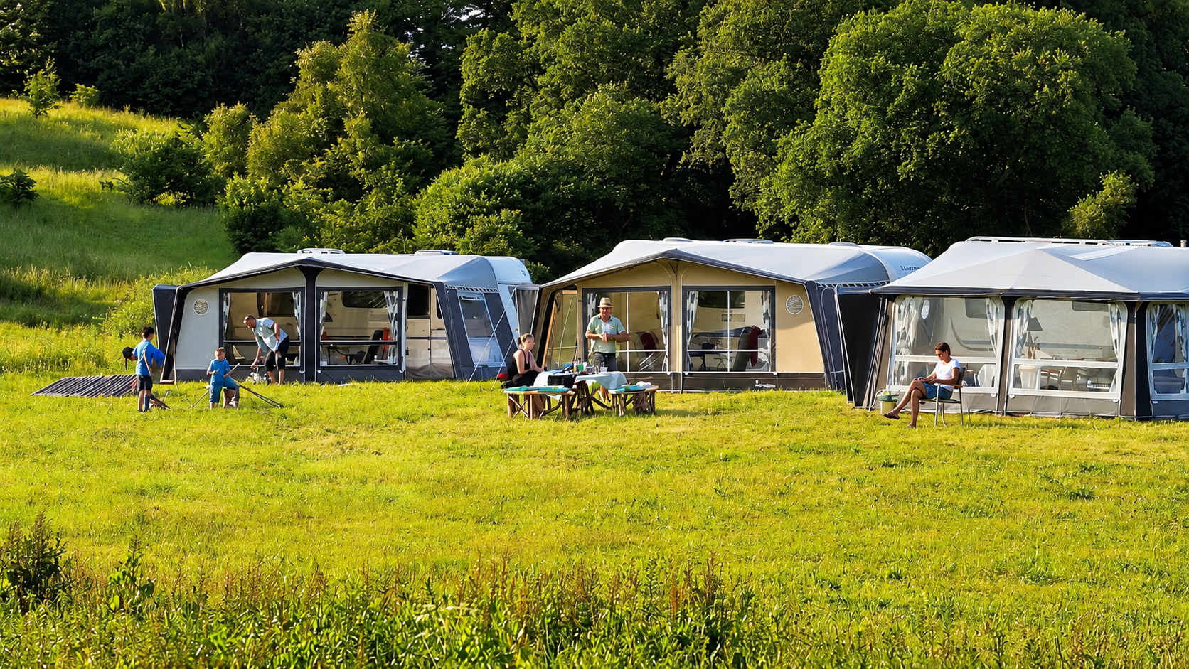 Wohnwagen mit Vorzelten auf einer grünen Campingwiese